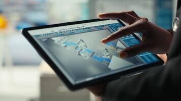 Photovoltaics factory specialist designs production lines in CAD app using tablet. Solar panels plant technician uses simulation software on device to optimize production layouts, camera B closeup video