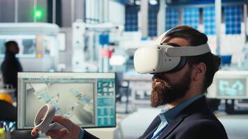 Photovoltaics factory engineer using VR goggles improving solar panels efficiency. Solar panels manufacturing plant worker using virtual reality tech researching cheaper solar solutions, camera A video