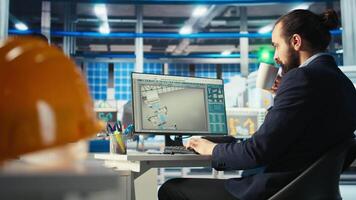 Man in photovoltaics factory monitoring system performance on PC screen. Solar panels manufacturing plant employee at computer desk tracking energy production and efficiency, camera A video