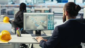 Photovoltaics factory worker drinks coffee, monitoring performance of robot arms placing solar panels on assembly lines. Man enjoys beverage at computer desk, inspecting solar plant machines, camera B video