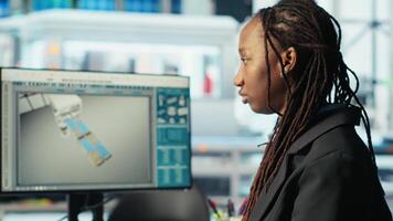 Photovoltaics factory programmer coding on PC to improve solar panels efficiency. African american software developer working in solar panels manufacturing plant, doing research, camera B video