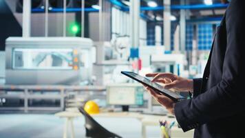 Engineer in photovoltaics factory using tracking software on tablet to diagnose malfunctioning systems. Solar panels manufacturing plant worker uses device to reduce downtime, camera A closeup video