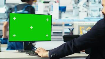 Photovoltaics factory worker monitors system performance on green screen PC. Solar panels manufacturing plant employee using chroma key computer to track energy production and efficiency, camera B video