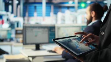 Solar panels plant employee uses CAD software on tablet to optimize layouts. Photovoltaics factory worker doing arrangements for maximum energy output using device, camera A close up video