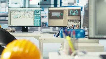 PC monitor in solar panels manufacturing plant used to study solar energy systems, closeup. Computer display on desk and hardhat in empty photovoltaics factory used to improve efficiency and innovate video