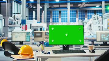 Isolated screen PC in photovoltaics factory used to monitor performance of robot arms manufacturing solar panels. Chroma key mockup computer in empty facility used to inspect solar plant machinery video
