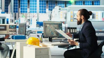 Photovoltaics factory manager looking over paperwork documents, monitoring system performance. Solar panels manufacturing plant administrator checking documentation files, tracking energy production video