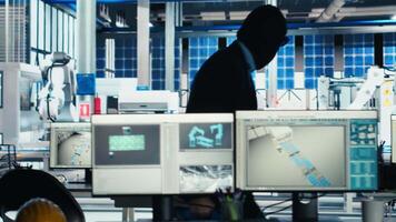 Masked worker in photovoltaics factory commits corporate espionage, stealing proprietary technology using USB stick. Man exploits insider access to copy trade secrets from solar panel plant, camera B video