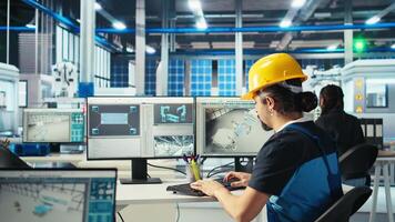 Photovoltaics factory engineer using PC to test robot arms placing solar panels on assembly lines. Professional sitting at computer desk inspecting solar plant heavy machinery units, camera A video
