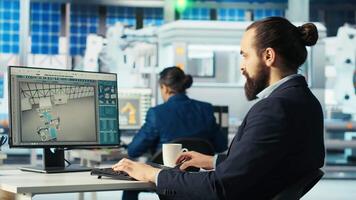 Photovoltaics factory engineer analyzing data on PC screen, reviewing system health metrics. Solar panels plant employee troubleshooting technical issues at computer desk, diagnosing faults, camera B video