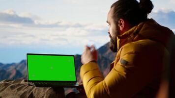 Thrilled traveler enjoying the panoramic beauty with a green screen device, looking out at the rugged mountain range. Endless landscape symbolize personal growth, freedom. Camera B. video