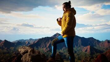 Determined traveler enjoys the solitude of a mountain summit, where the panoramic view represents adventure and personal growth. Hiker feeling cold on the windy mountain top. Camera A. video