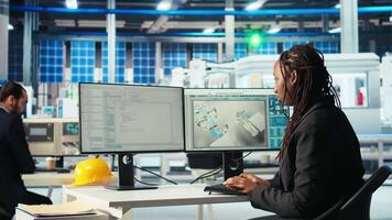 Programmer in photovoltaics factory using PC program to diagnose malfunctioning systems. Woman coding at computer desk in solar panels manufacturing plant, reducing downtime, camera A video
