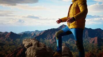 Proud explorer basks in the joy of accomplishment standing at the mountain peak with arms lifted, mindfulness. Traveler admiring stunning scenic view and vast sky for the thrill of hiking. Camera A. video
