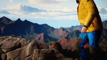 Determined trekker looks out at the epic mountain range and sightseeing, inspired by the vastness of the sky and the rugged peaks. Reward of embracing the great outdoors. Camera A. video