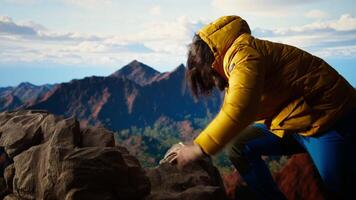 Foolish hiker tripping and losing balance on the rocky mountain peak, struggling to climb unequipped in the extreme wilderness. Dangerous landscape for an unprepared explorer. Camera A. video