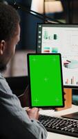 Vertical Young guy examining funds for a program and holding tablet with mockup, studying finances and accounting management on a software. Male specialist doing remote work for a startup. Camera B. video