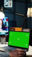 Vertical Teleworker at home editing documents next to mockup on his laptop, submitting reports and files before deadline. Black freelancer managing digital paperwork within the work platform. Camera A. video
