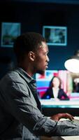Vertical Young filmmaker working on media post production from agency office, ensuring editing timeline and color grading for a shoot. Tech driven workspace showcases a digital workflow. Camera A. video