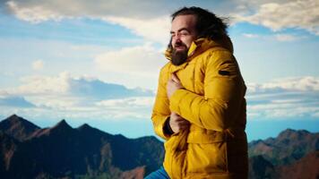 Young traveler hiker dealing with cold weather and wind at the mountain top, feeling proud with his personal achievement. Nature lover struggles to climb due to bad weather. Camera A. video