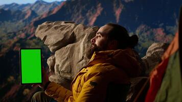 Adventure seeker stands at a mountain peak next to isolated chroma key, looking out at the scenic view that stretches endlessly before him. Fresh air and breathtaking landscape. Camera A. video