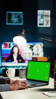 Vertical African american man working from home with green screen on laptop, looking at data on the web. Remote worker in personal apartment office crosschecking important info. Camera A. video