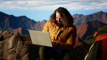 Hiker defies the harsh winds and cold weather to stay connected online, camping in the windy risky wilderness. Explorer with technology addiction connected even on mountain top. Camera B. video