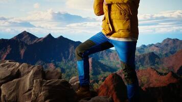 Determined climber gazes at the sky and rocky mountain tops, reflecting on the resilience and ambition needed to push beyond limits. Breathtaking skyline view inspires adventure. Camera A. video