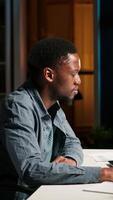 Vertical Focused remote worker balancing freelance tasks and researching data online, drafting notes and information for articles. Black person working at home, planning schedule and projects. Camera B. video