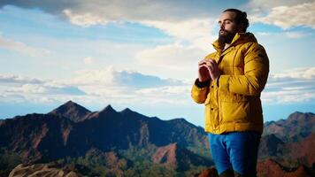 Young explorer reaching the mountain peak and meditating at the top, doing a zen meditation with calm and mindfulness. Happy content hiker loving nature for self care. Camera A. video