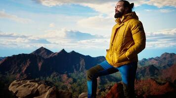 Adventure seeker in warm clothing enjoys the serenity of the wilderness, panoramic mountain top view and open sky create the perfect setting for relaxation. Cold winds uphill. Camera A. video
