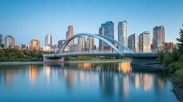 A modern bridge spans a river, framed by a city skyline at dusk photo