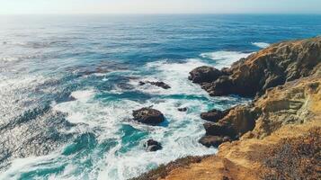 A scenic coastal view showcasing waves crashing against rocky cliffs under a clear sky photo