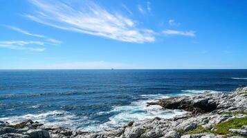 A serene coastal landscape with rocky shores and a clear blue sky over the ocean photo