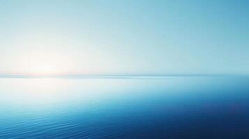 A serene seascape with calm waters and a soft blue gradient sky at sunrise. photo