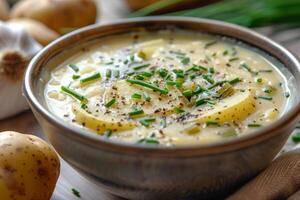 A bowl of creamy potato soup garnished with chives and black pepper photo