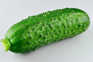 A fresh cucumber covered in water droplets, showcasing its vibrant green color and texture photo