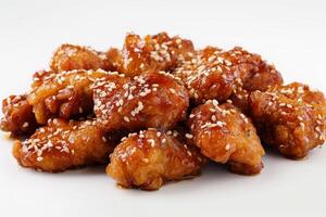 A pile of crispy, glazed chicken pieces topped with sesame seeds photo