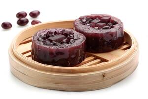 Two round jelly desserts with red beans, served in a bamboo steamer photo