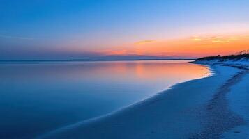 A serene beach at sunset, showcasing calm waters and a colorful sky photo