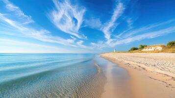 A serene beach scene with calm waters and a lighthouse in the distance under a blue sky photo