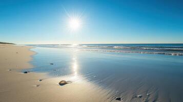 A serene beach scene with gentle waves and a bright sun reflecting on the water photo