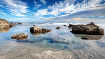 A serene beach scene with rocks and clear water under a blue sky photo