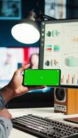 Vertical Young person does remote work using data finances with a green screen, examining statistics at his workstation. Investment advisor planning new strategy to obtain funds for development. Camera A. video