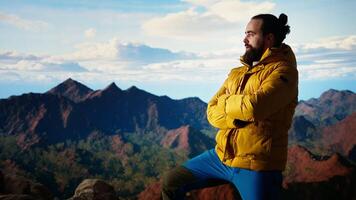 Thrilled adventurer celebrates reaching the mountain summit, embodying the spirit of determination and endurance. Hiker enjoying panoramic landscape of a mountain range. Camera A. video