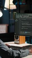 Vertical Black man programmer manages code and scripts in artificial intelligence and machine learning on dual monitors computer setup. Male freelancer uses pc to guarantee cyber security. Camera B. video