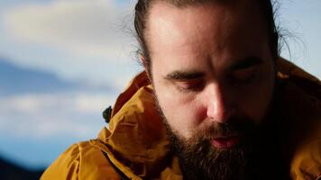 Satisfied adventurer celebrates personal success on a mountain peak, taking a breath and enjoying the scenic view at the top. Motivation for adventure and outdoor exploration. Camera B. video