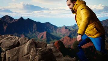 Adventure seeker gazes at the valley and mountain peaks ahead, feeling the freedom of the open wilderness. Young man fully equipped enjoying high altitude outdoor exploration. Camera A. video