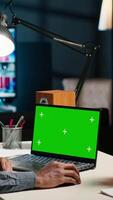 Vertical Black man creating a report with data next to isolated chroma key display, improving his skills and achieving career independence. Remote worker solving daily freelance tasks. Camera B. video