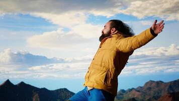 Happy adventurer embraces the thrill of standing at the top of the mountain, feeling the power of accomplishment. Awe inspiring mountain range with peaceful sky and vast wilderness. Camera B. video